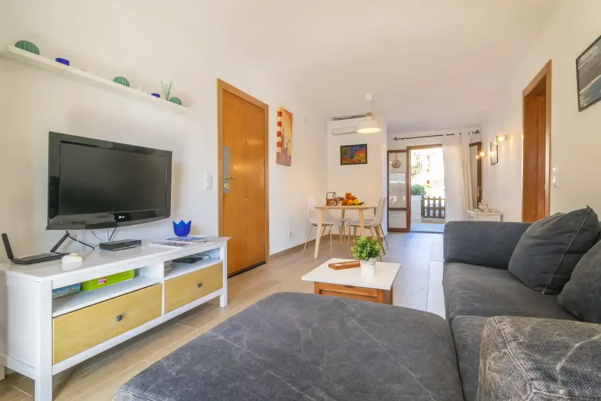 Living room with seating, a television, and a dining table near the balcony.