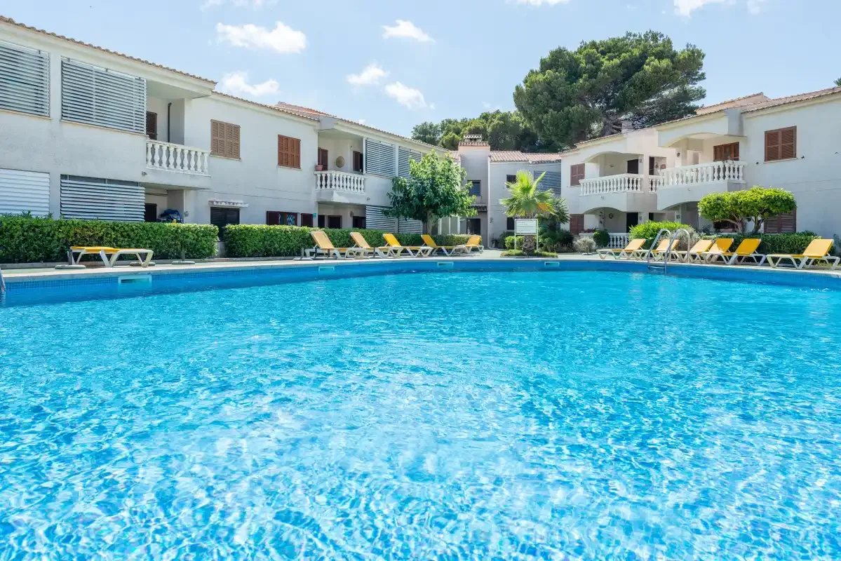 A swimming pool surrounded by apartment-style buildings and lounge chairs.