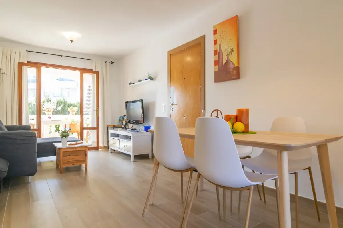 A bright living and dining area with a table, seating, and a television.