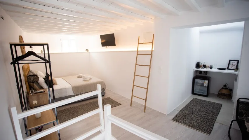 Dormitorio luminoso con una litera, una escalera y una pequeña zona de estar.
