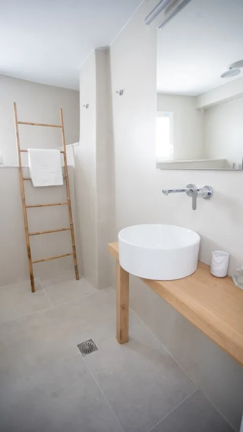 A bright bathroom with a basin on a wooden counter and a towel ladder.