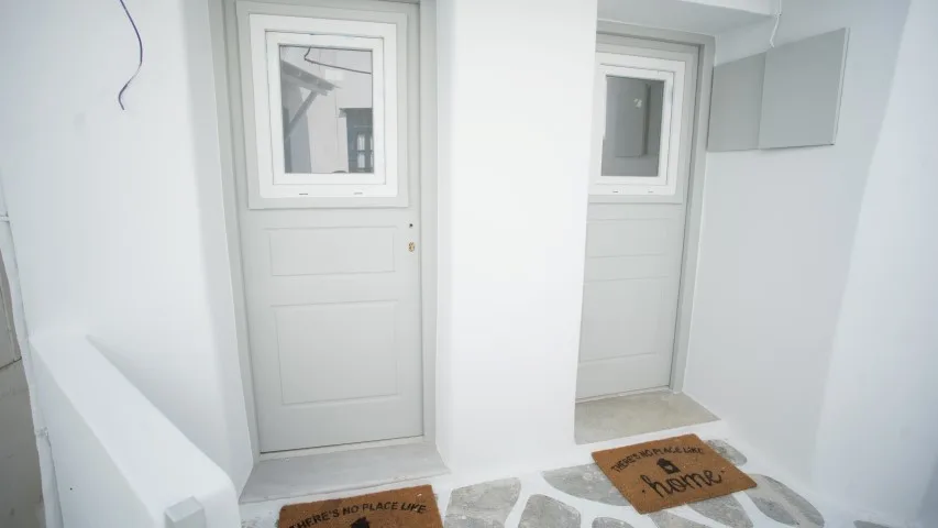Una entrada blanca y luminosa con dos puertas y baldosas estampadas.