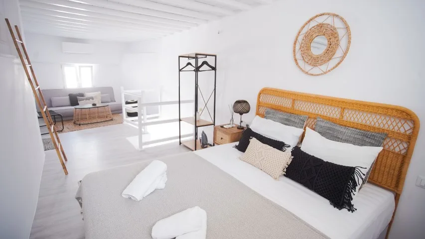A bright bedroom with a woven headboard and a white bed.