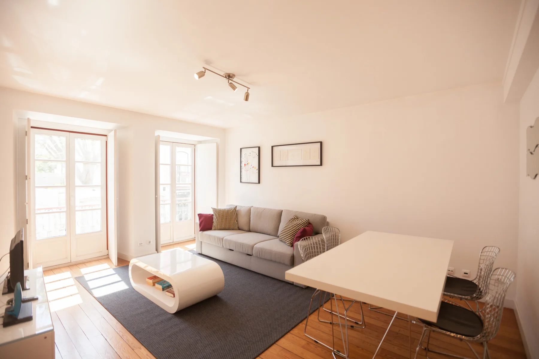 Una sala de estar luminosa con sofá, mesa de centro y comedor.