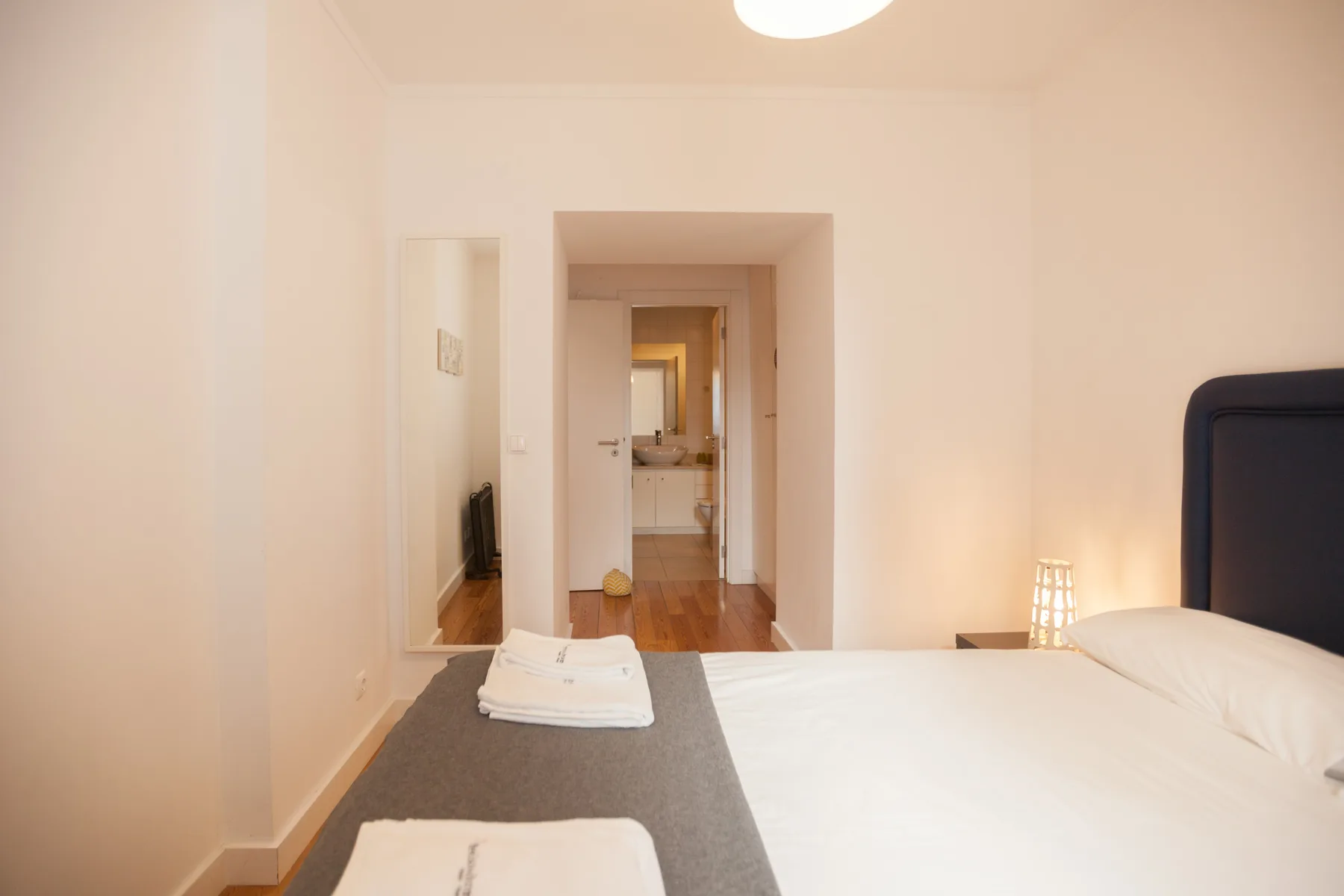 Un dormitorio luminoso con una cama y una puerta que da a un baño.