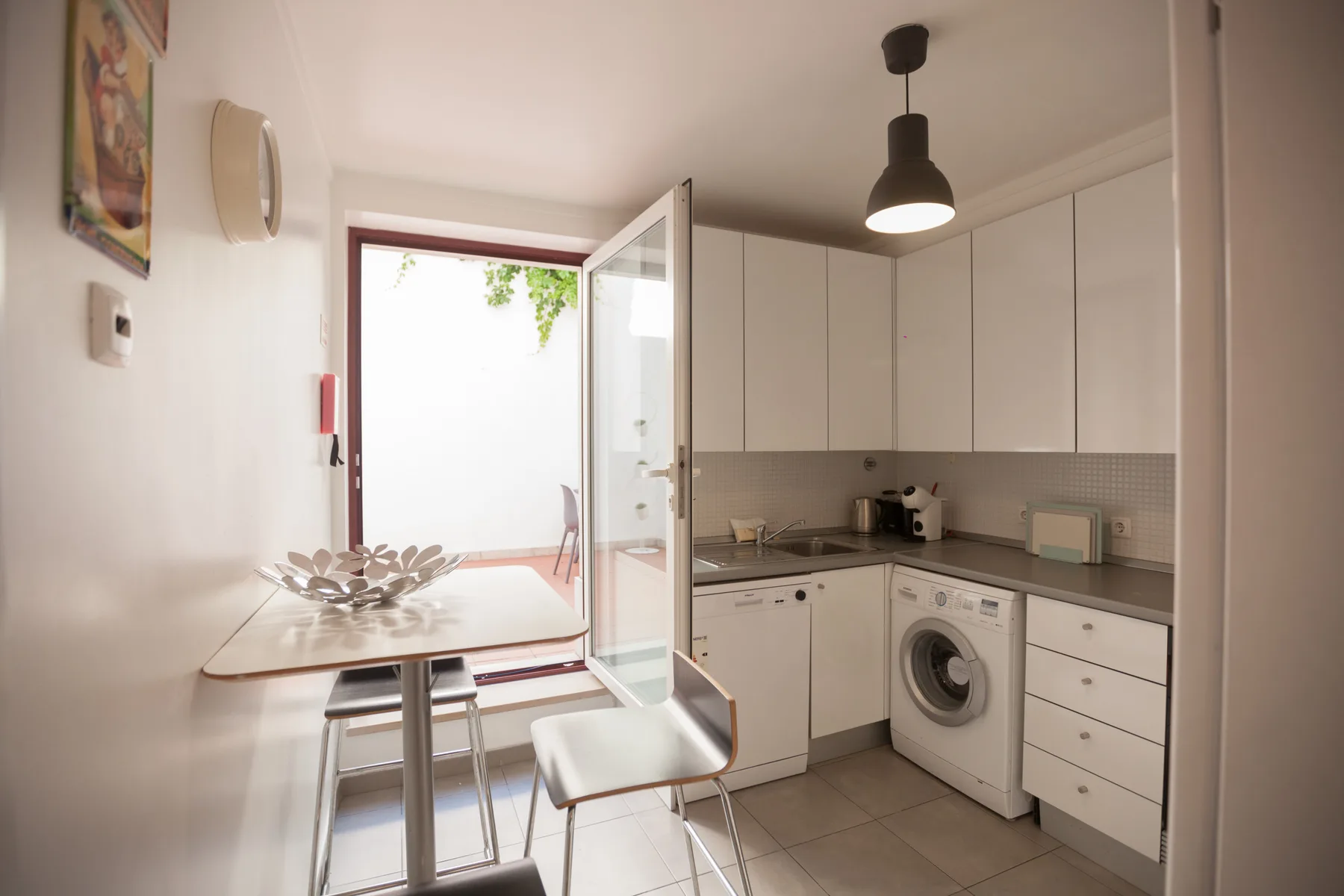 Una cocina compacta con una mesa pequeña junto a una puerta abierta.
