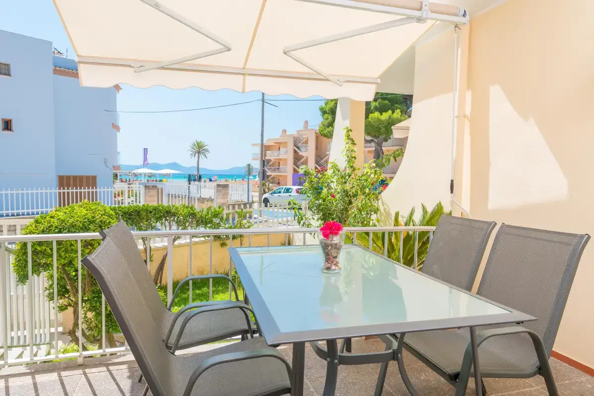 A shaded balcony dining area overlooks nearby buildings and the seaside.