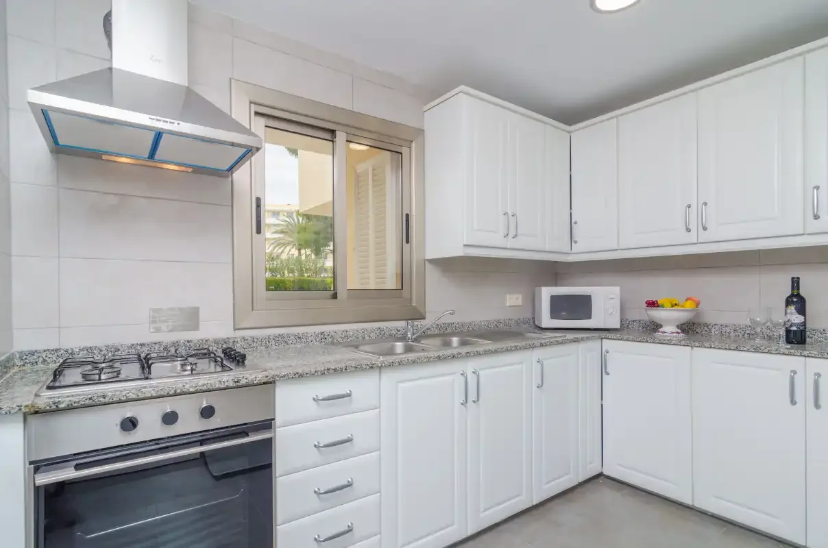 A bright kitchen with white cabinets, a countertop, and a window.