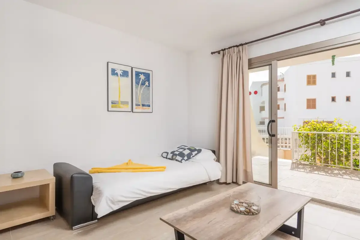 A bright room with a daybed and sliding glass doors opening onto a balcony.