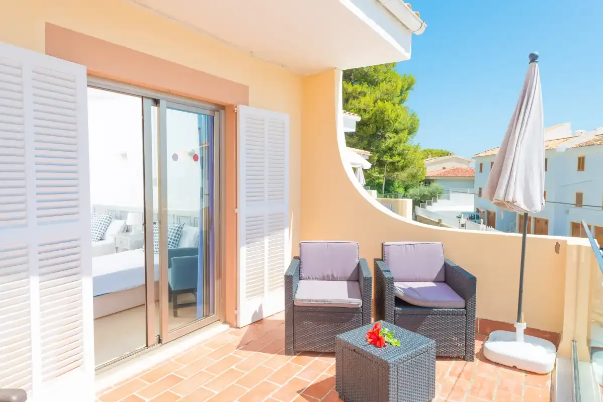 A sunny balcony with outdoor seating and a closed patio umbrella.