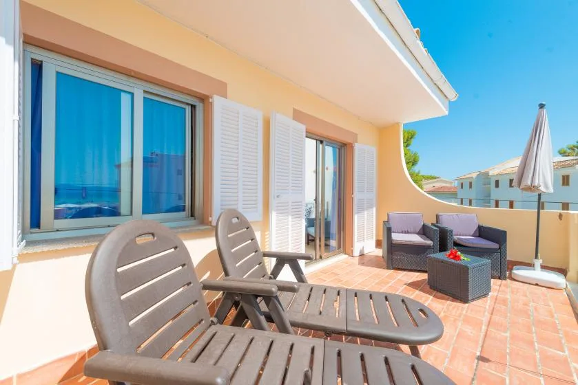 A sunny patio with lounge seating and windows overlooking the surrounding buildings.