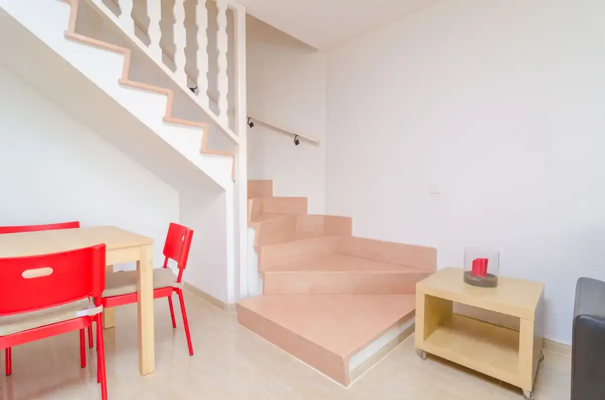 A bright interior shows a staircase beside a small dining area.