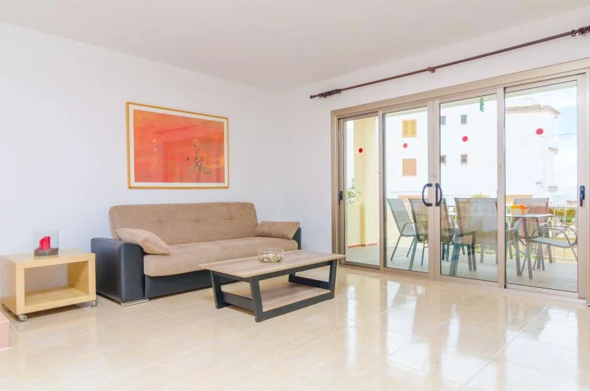 A bright living room with seating and a coffee table beside sliding glass doors.