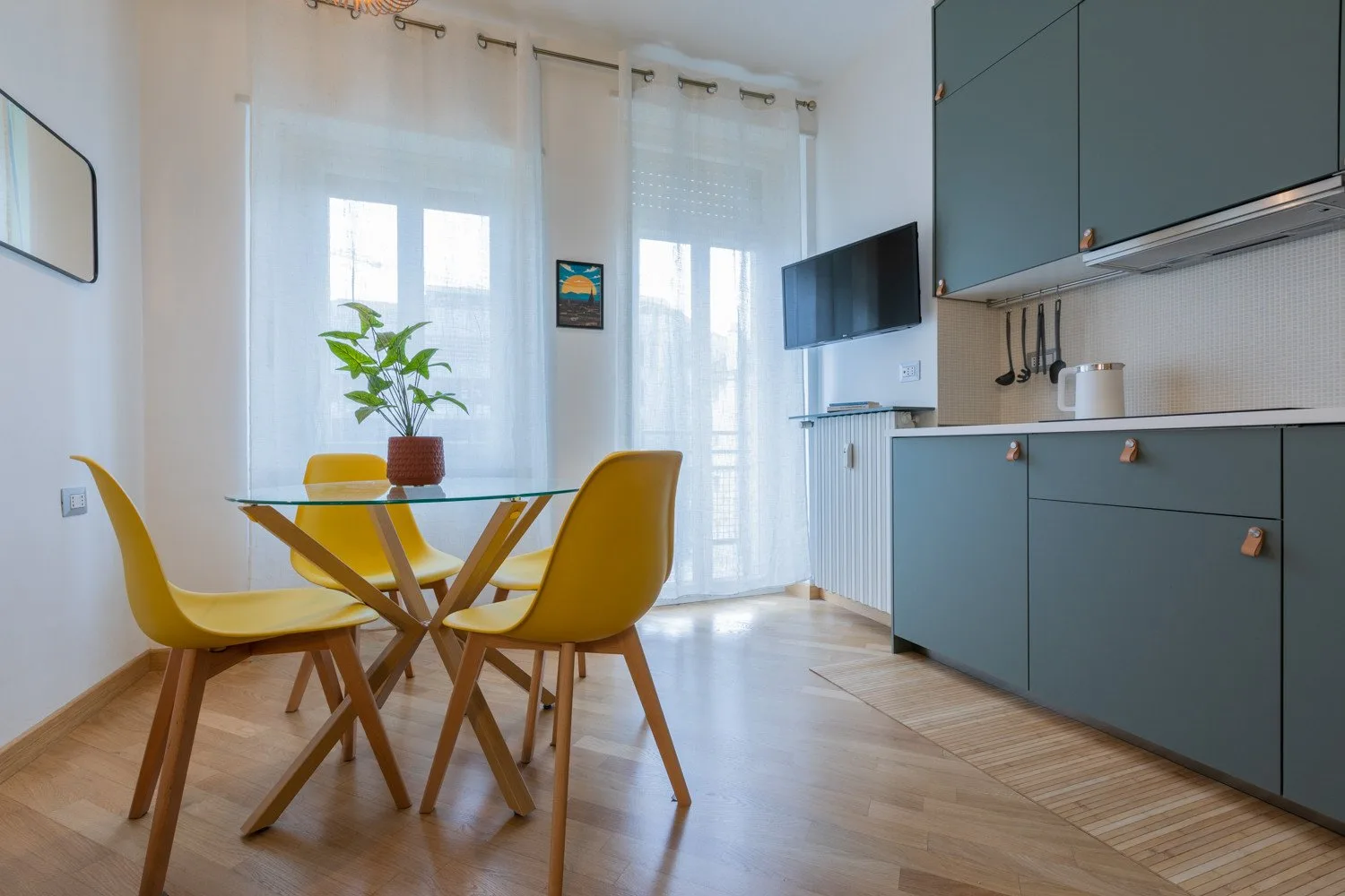 A kitchen and dining area with yellow seating beside bright windows.