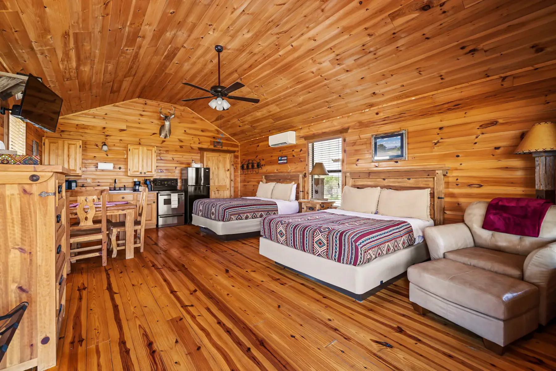 Una habitación revestida de madera con dos camas, un pequeño comedor y asientos.