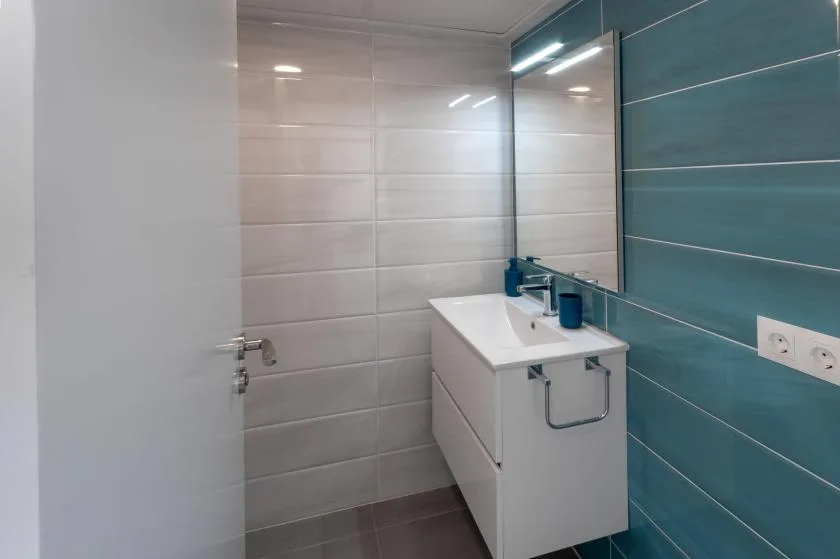 A modern bathroom with a white vanity and a large mirror.
