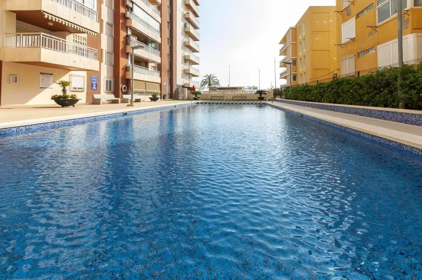 An outdoor swimming pool sits between apartment buildings.