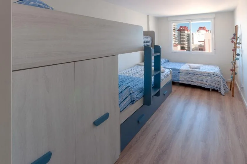 A bedroom with bunk beds and a separate bed beside a window.