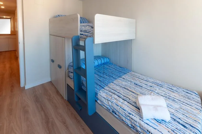 A bunk bed with blue-striped bedding sits in a bright bedroom.