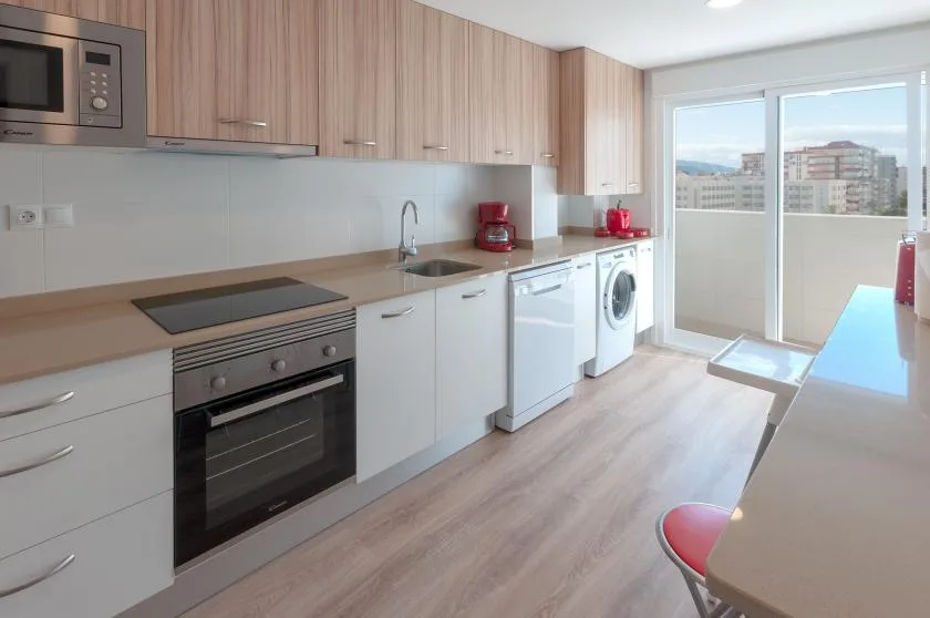A modern kitchen with built-in appliances and a sliding glass door opening onto a balcony.