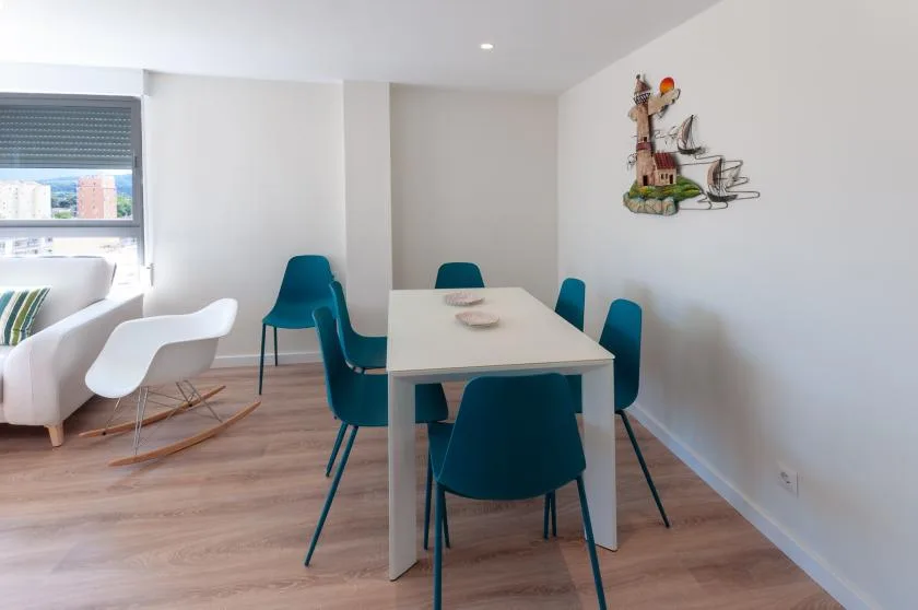 A dining area with a white table and teal seating beside a window.