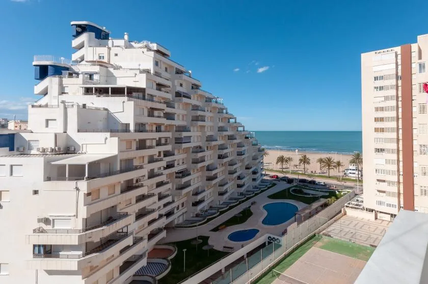 A coastal apartment complex overlooks a landscaped courtyard and the sea.