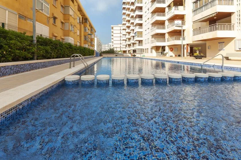 An outdoor swimming pool sits between apartment buildings.