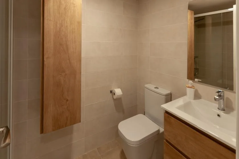 A tiled bathroom with a toilet, sink, and large mirror.