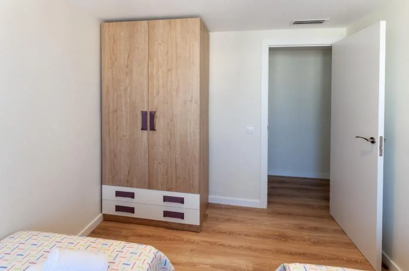 A bedroom with a wooden wardrobe and an open doorway.