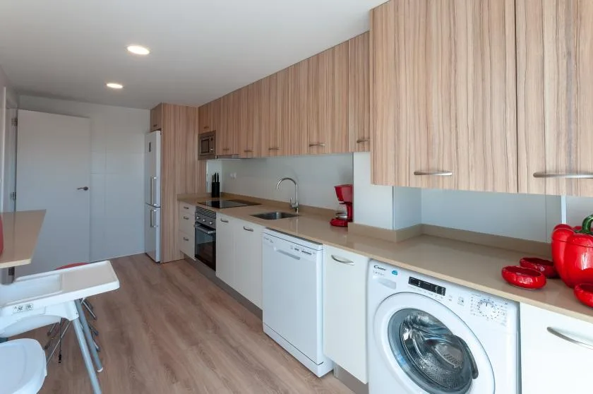 A modern kitchen with wood cabinets, a countertop, and laundry appliances.