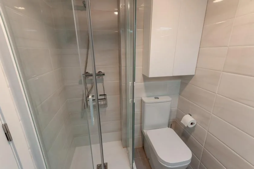 A tiled bathroom with a glass shower and toilet.