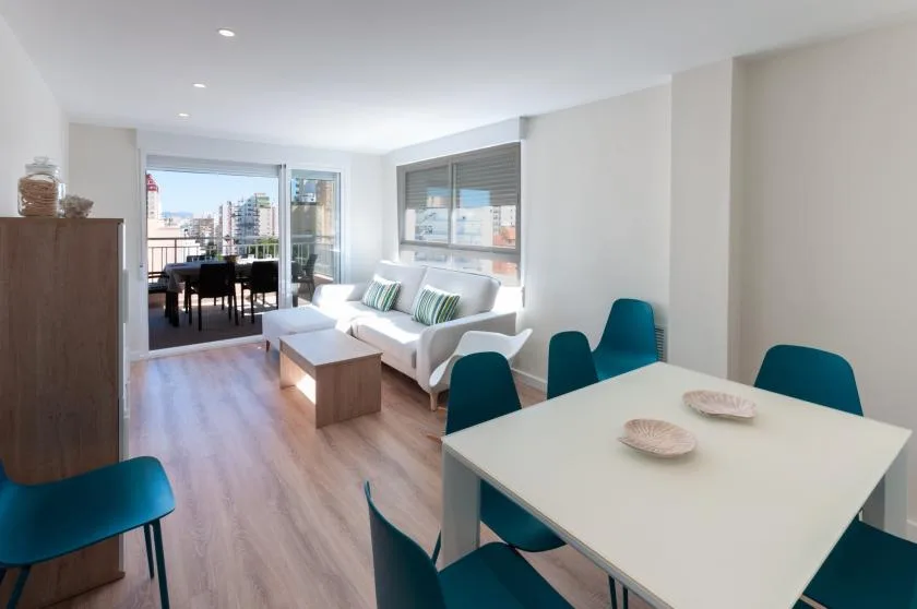 A bright open-plan living and dining area with a white sofa and dining table.