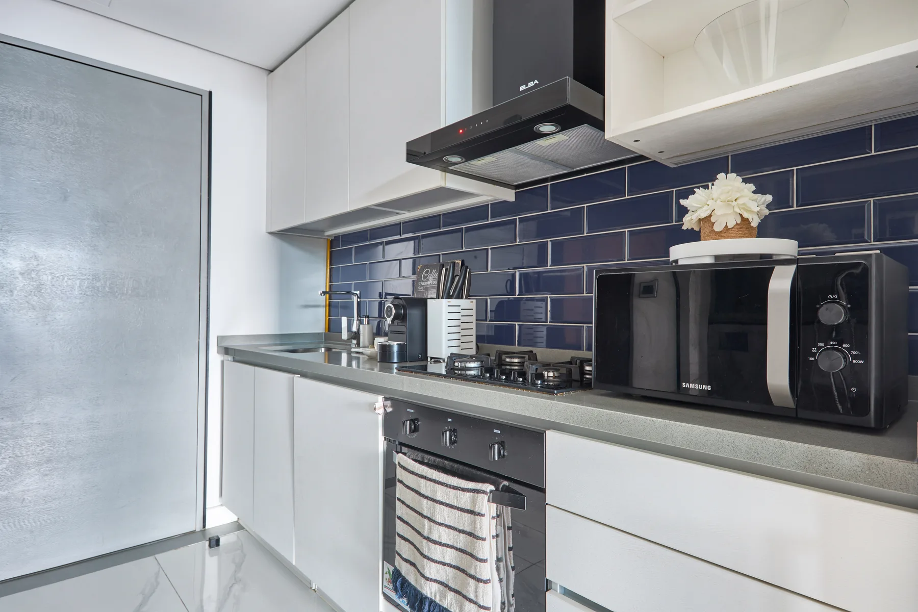 A modern kitchen with a dark tiled backsplash and countertop appliances.