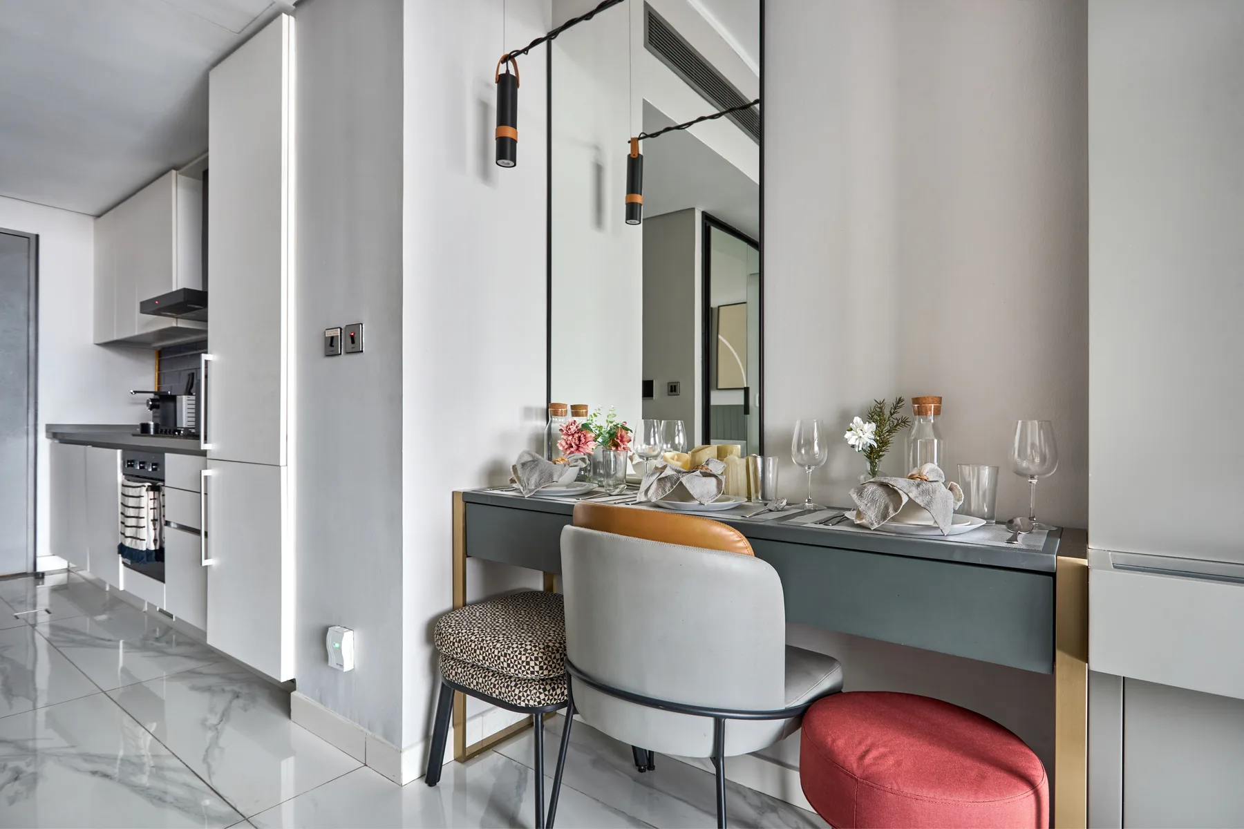 Comedor con la mesa puesta y asientos tapizados junto a una cocina compacta.