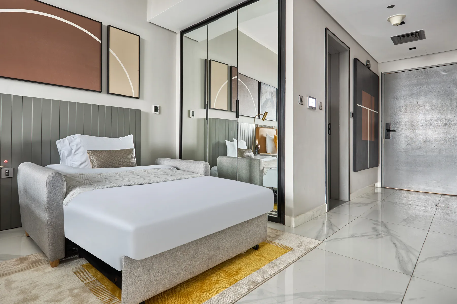 A bedroom with a bed, wall art, and mirrored closet doors.