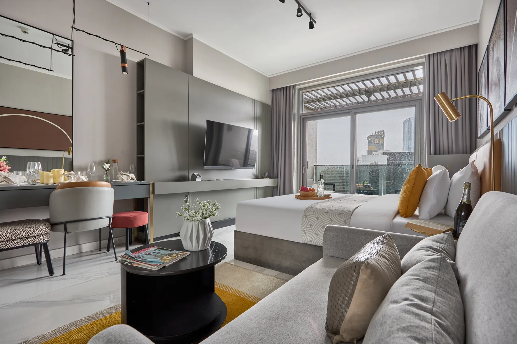 Un dormitorio moderno con zona de estar y una cama junto a ventanales.