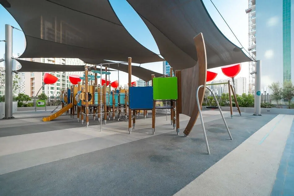 An outdoor playground with colorful play equipment beneath large shade canopies.