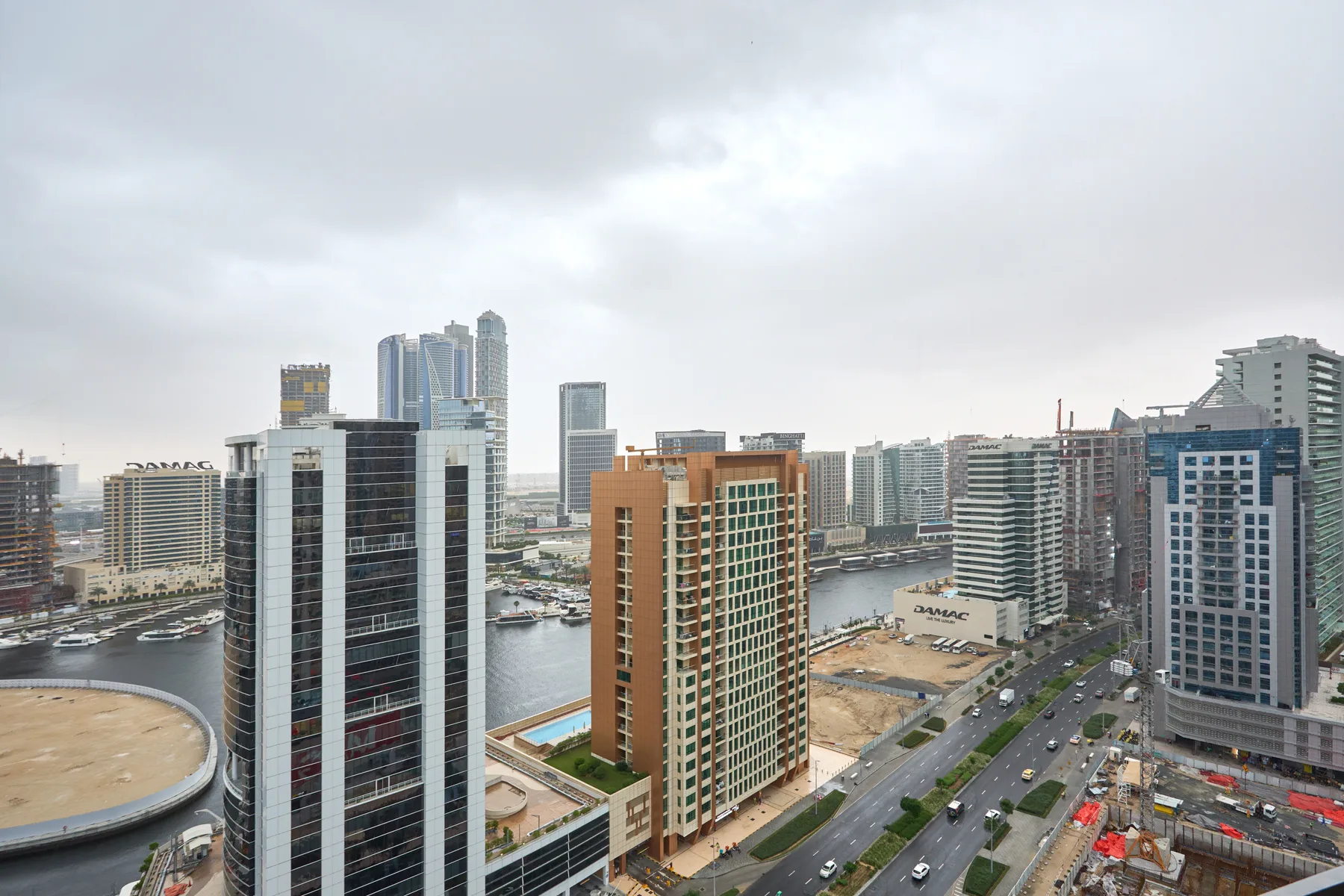 A city waterfront skyline with high-rise buildings, a waterway, and a road.