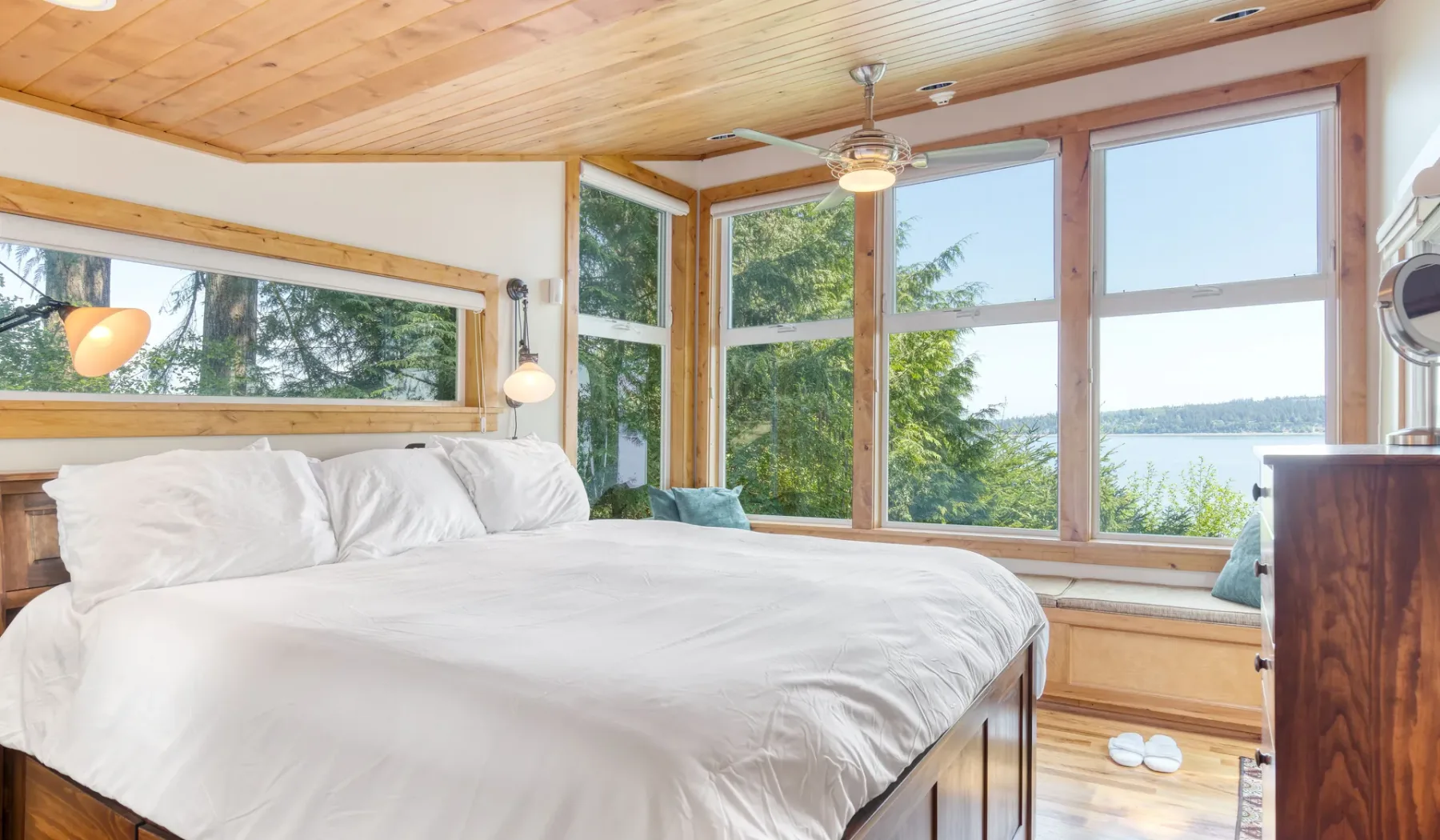Dormitorio con una cama grande junto a ventanas con vistas al agua.