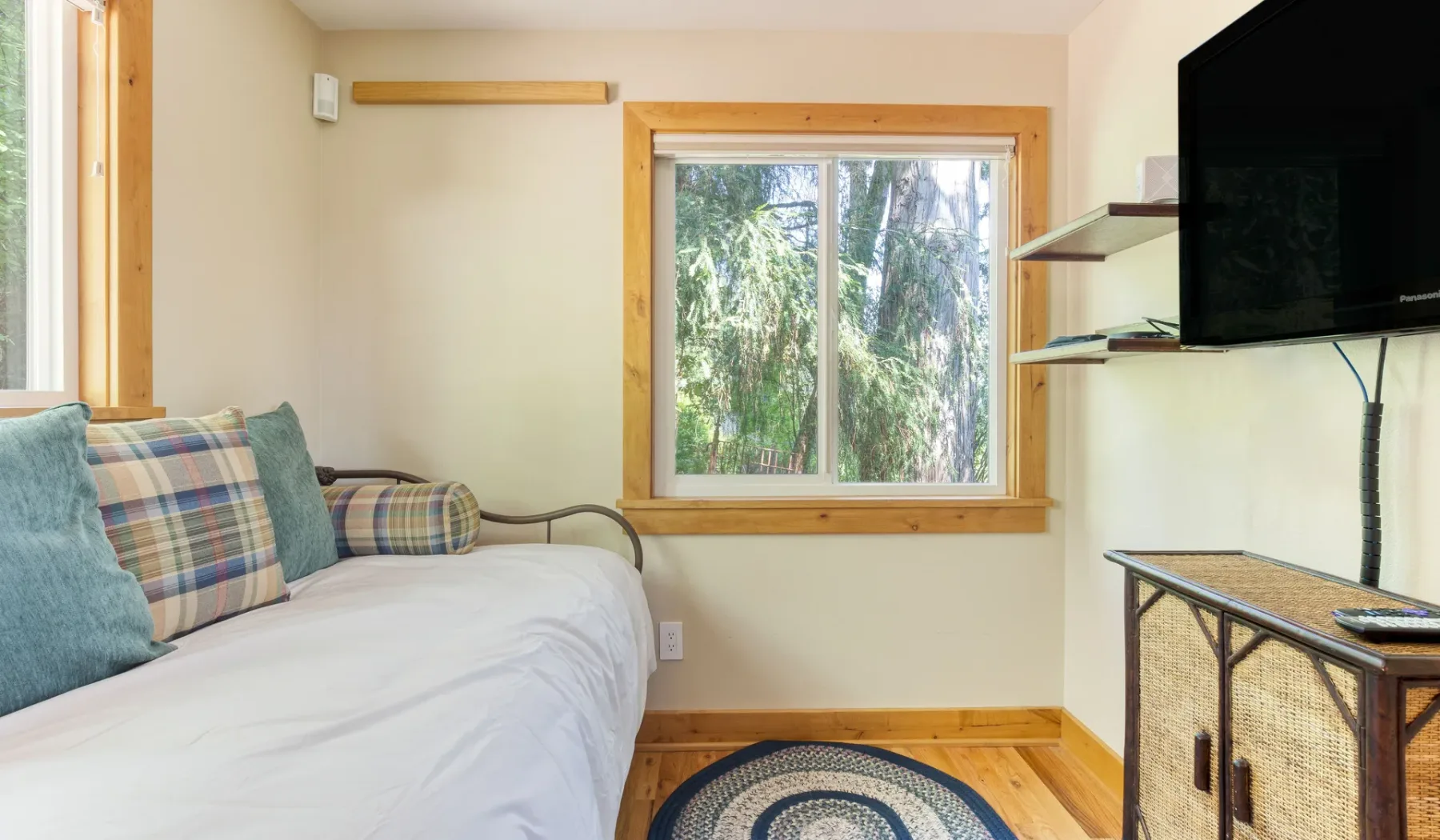 Una zona de descanso con una cama, una ventana y un televisor en la pared.