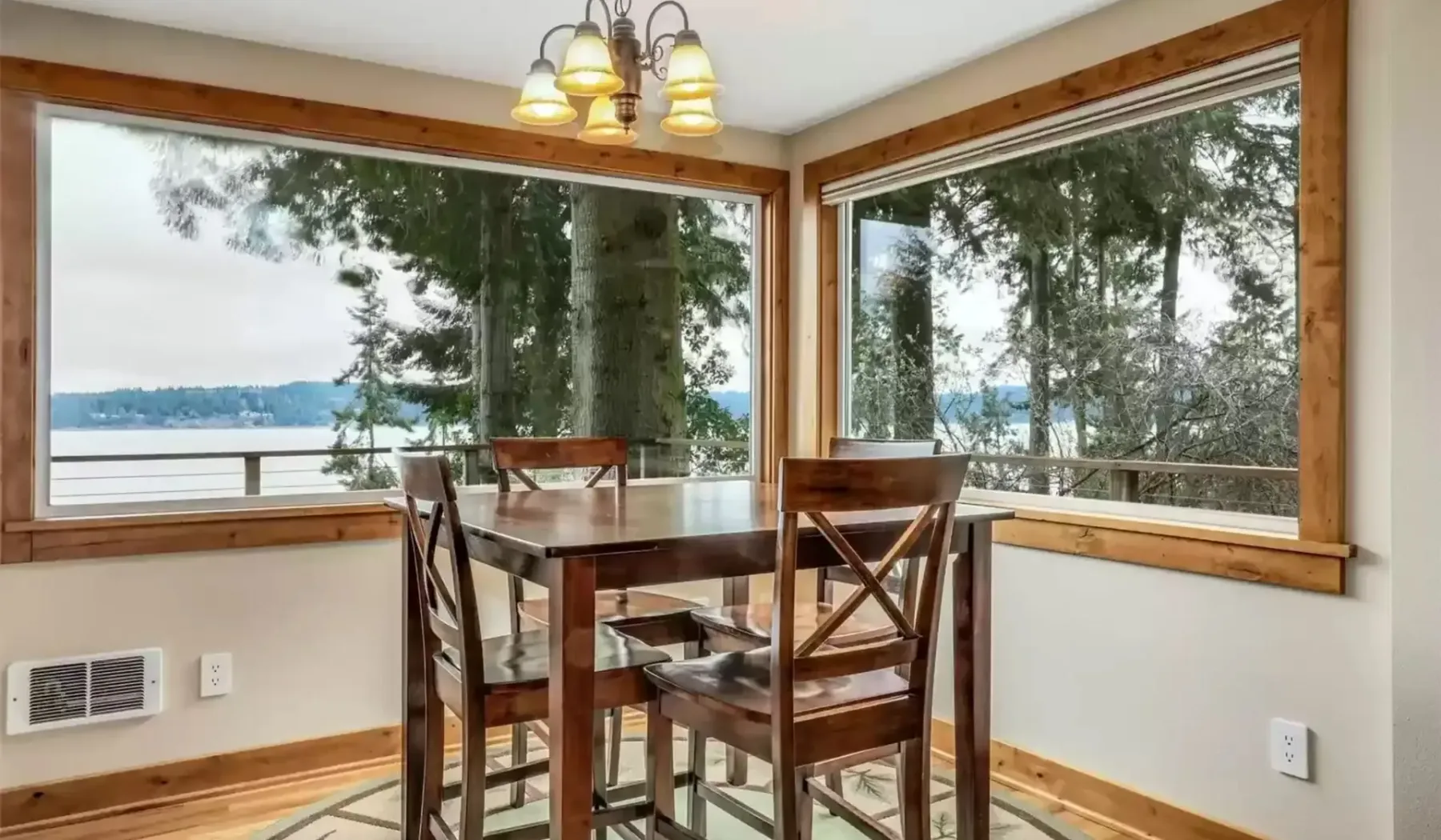 Comedor con asientos de madera junto a grandes ventanas con vista al agua.
