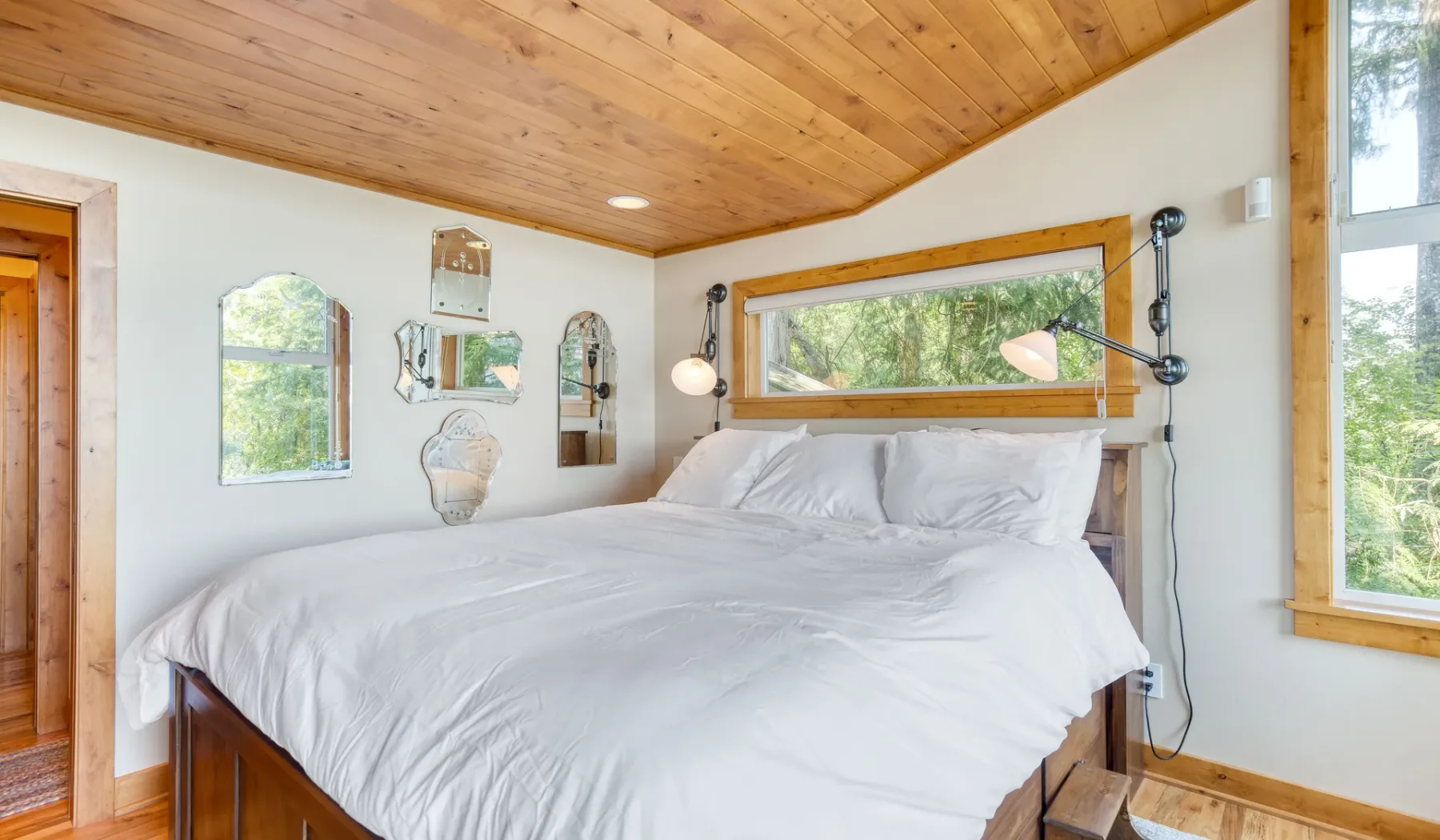 Un dormitorio con una cama debajo de una ventana horizontal amplia.