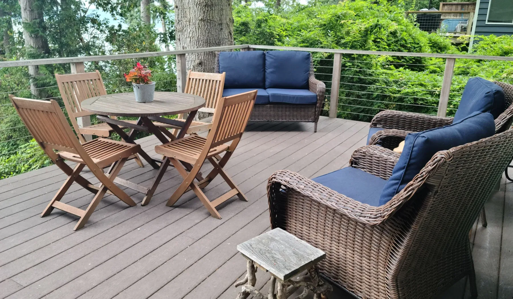 Una zona de estar en una terraza exterior con mesa y sillones acolchados.