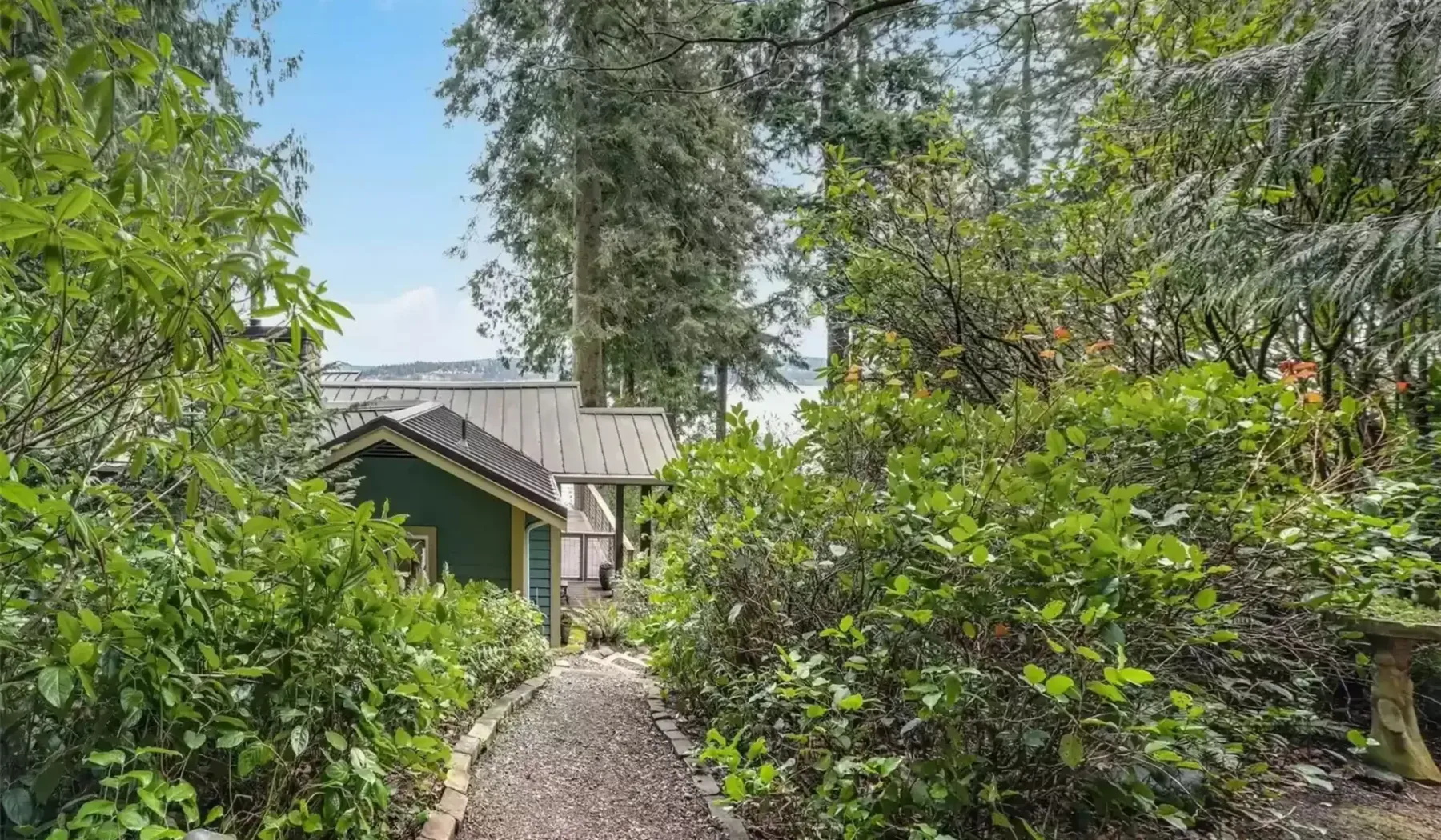 Un sendero de jardín atraviesa la vegetación y conduce a un edificio pequeño.