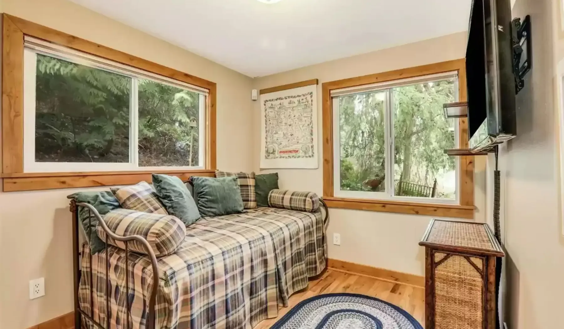 Un dormitorio con una cama a cuadros y ventanas con vistas a los árboles.