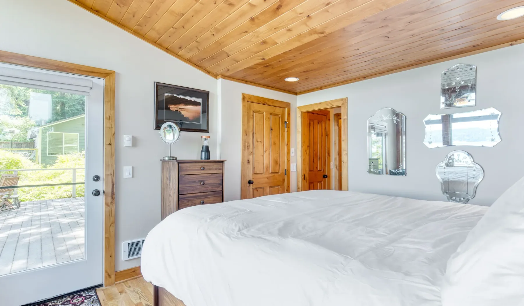 Un dormitorio con una cama grande, techo de madera y puertas que dan a la habitación.
