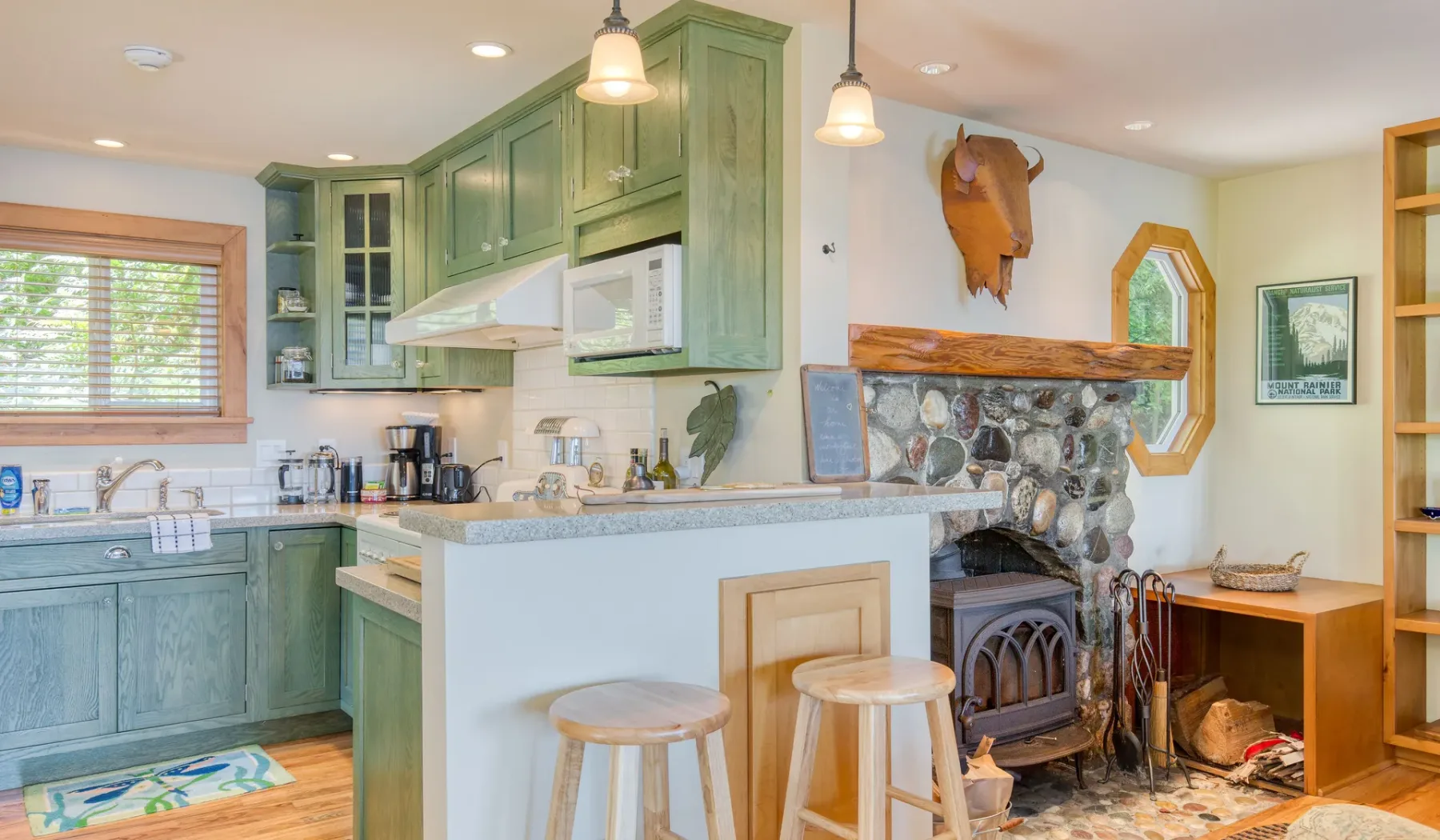 Una cocina verde con una barra junto a una chimenea de piedra.