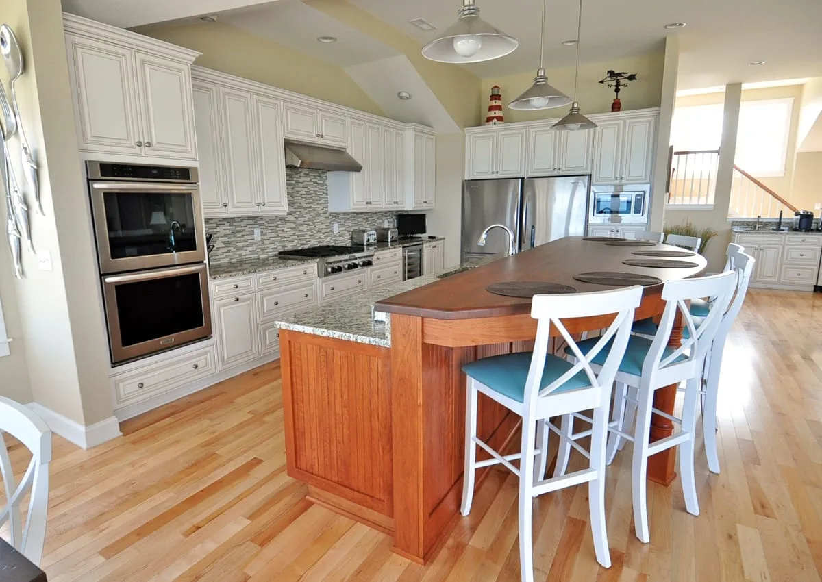 Una cocina amplia con una isla de madera y asientos blancos.