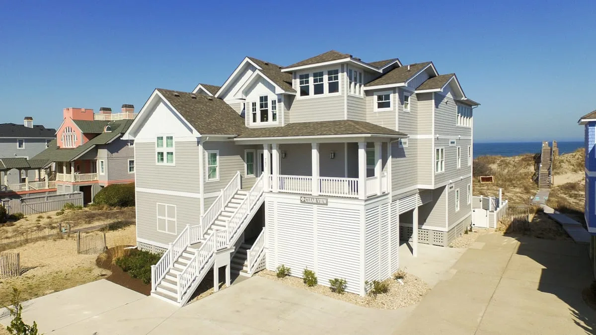 Una casa costera grande con revestimiento blanco y escaleras exteriores.