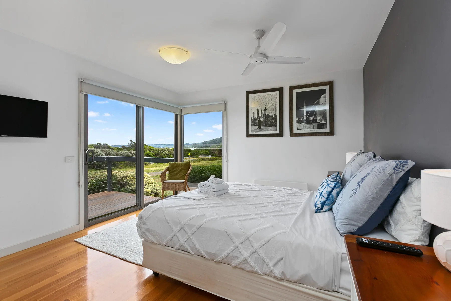Un dormitorio luminoso con una cama junto a grandes puertas de vidrio con vistas a la vegetación.